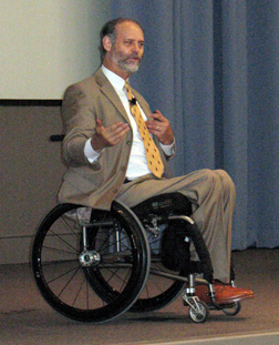 Photo of Gary Karp Speaking and Audience Applauding